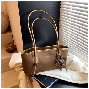 Detail of a brown suede tote bag with slim knotted straps and soft window light shadows