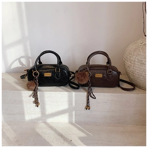 Detail view of premium Boston-style bags in black and dark brown with fuzzy ball charms
