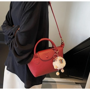 Detail of red dumpling bag with lychee texture and cute white plush sheep charm