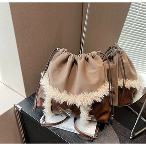 Detail of a brown leather bucket bag with plush trim and silver butterfly ornament