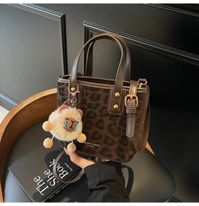 Detailed view of leopard print bucket bag texture with gold hardware and plush bear charm