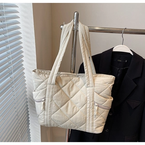 Close-up of quilted tote bag with side zipper pocket and elegant diamond pattern