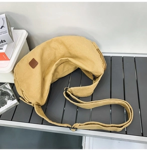 Detail einer senfgelben Segeltuch-Halbmondtasche mit Lederpatch und Metallreißverschluss