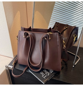 Detailed view of dark brown tote bag showing matte leather texture and gold hardware