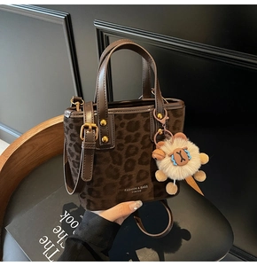 Close-up of leopard print bucket bag with leather handles and plush sheep pendant