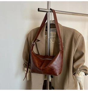 Detail of dark brown leather half-moon bag with adjustable wide shoulder strap and zipper