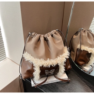 Detail of faux shearling bucket bag with silver butterfly buckle on makeup table