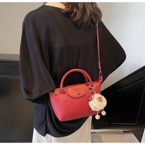 Detail of red dumpling bag with pebble grain texture and cute white alpaca charm pendant