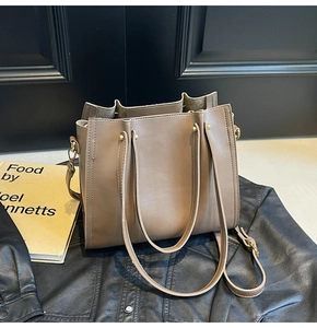 Close-up of khaki tote bag texture with gold hardware on a stylish leather jacket