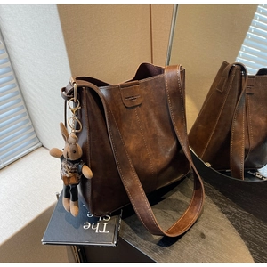 Detail of vintage dark brown leather bucket bag featuring fashion embossing and rabbit charm