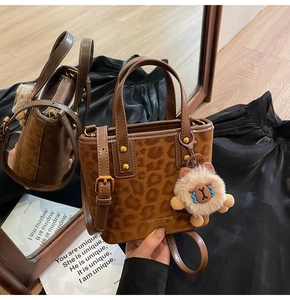 Detail view of leopard print bucket bag with metal rivets and plush animal charm accessory
