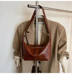Detailed view of a brown vintage half-moon hobo bag hanging with stylish autumn clothes