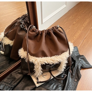 Detail of dark brown bucket bag with plush trim and silver butterfly ornament