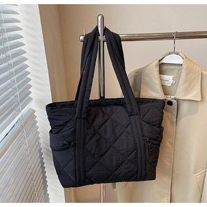 Detail of black quilted tote bag with side zippers and soft rhombus stitching pattern
