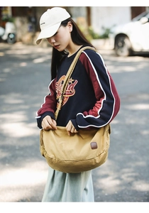 Detailansicht der Khaki-Canvas-Umhängetasche mit Vintage-Lederaufnäher im Freien