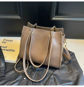 Close-up of brown faux leather tote bag showing gold rivets and smooth material texture