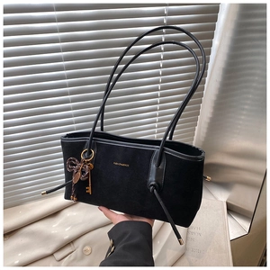 Detail of black suede tote bag with golden branding and metal key charm pendant