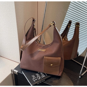 Detail of coffee brown tote bag with metal brand plaque and contrast PU leather strap
