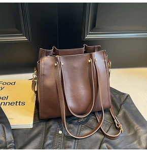 Detail view of large dark brown leather tote bag with gold studs and adjustable strap