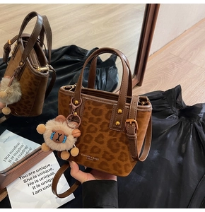 Detail of leopard print bucket bag with brown leather trim and cute plush bear charm