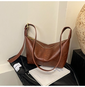 Close-up of brown leather crescent bag with adjustable strap and metal zipper detail