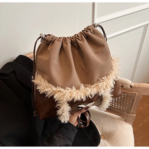 Detail of plush faux fur drawstring bag with metal bow buckle on beige canvas fabric