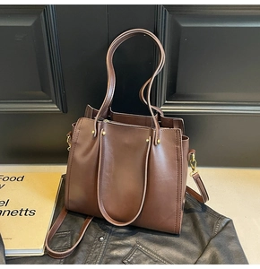 Detailed macro view of dark brown faux leather texture and vintage gold hardware on tote bag