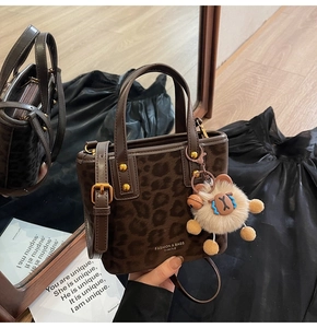 Detail of leopard print bucket bag with gold studs and plush alpaca charm accessory