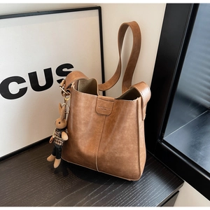 Detail of vintage brown bucket bag featuring lychee texture and cute rabbit charm