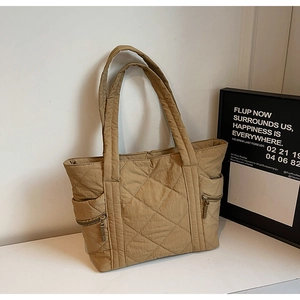 Detail of khaki quilted tote bag featuring lateral zipper pockets and wide shoulder straps