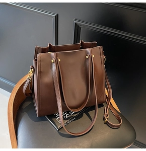 Close-up of matte dark brown tote bag with champagne gold hardware on a wooden chair
