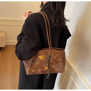 Détail d'un sac cabas en cuir marron avec logo en métal triangulaire et grigri