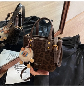 Detail of leopard print velvet bucket bag with plush alpaca charm and logo strap