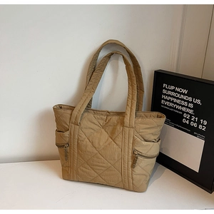 Detail view of khaki quilted nylon tote bag with side zippers and diamond pattern
