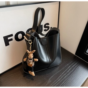 Detail of matte black bucket bag featuring a bunny charm and vertical stitched seam