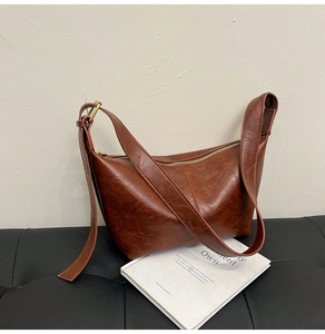 Detail view of brown vintage hobo bag showing oily leather texture and gold hardware