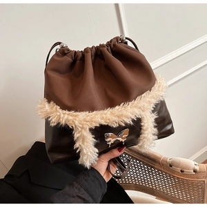 Detail of drawstring bucket bag with brown leather, fur trim, and golden butterfly clasp