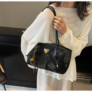 Détail du sac cabas en nylon brillant avec logo triangle et breloque tressée