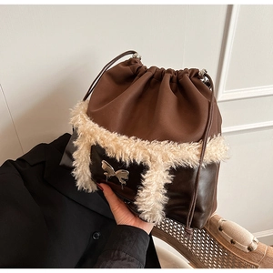 Detail of drawstring bucket bag with brown leather, plush trim and silver butterfly charm