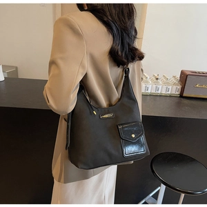 Detailed side view of a black nylon tote bag with golden metal logo and leather pocket