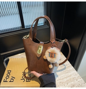 Close-up of brown bucket bag with gold twist lock and cute plush animal charm