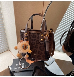 Detail of leopard print bucket bag with gold studs and plush bear charm decoration