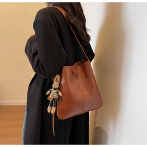 Detail of vintage brown bucket bag with soft sheen, vertical stitching, and rabbit charm
