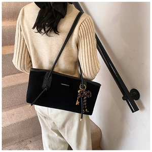 Detail of matte black suede tote bag with golden lettering and bow key charm