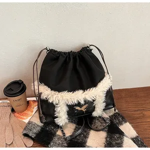 Detail of drawstring bucket bag with faux fur trim and metal butterfly logo on wood