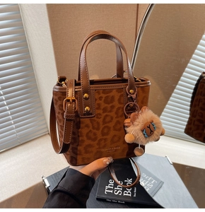 Detail of leopard print bucket bag with plush lion charm and adjustable shoulder strap