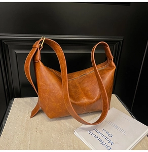 Detail of vintage brown leather hobo bag with smooth texture on a minimalist stone surface