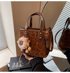 Detail of leopard print suede tote bag with plush charm and branding in a stylish setting