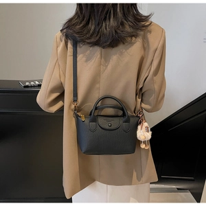 Detail of black lychee leather crossbody bag with top handles and plush ball charm