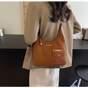 Detail of caramel leather shoulder bag featuring a front pocket with golden metal buckle